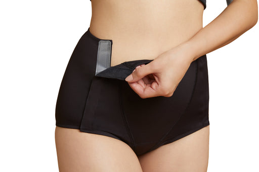 Close-up of a model wearing Slick Chicks Adaptive Leakproof Underwear in black, pulling open the VELCRO Brand Fasteners with one hand against a plain white background
