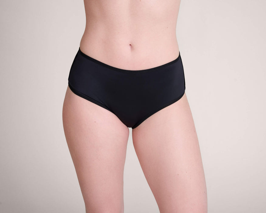 Front angle of a model wearing Slick Chicks Adaptive Pull-On Boyshort against a plain beige background
