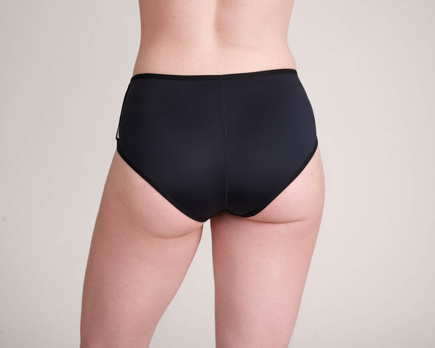 Back angle of a model wearing Slick Chicks Adaptive Pull-On Boyshort against a plain beige background