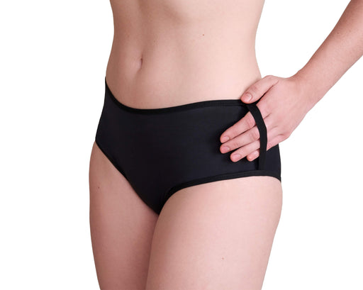 Close-up of a model wearing Slick Chicks Adaptive Pull-On Boyshort in black, showing the side straps with their hand inside pulling it up, against a plain white background