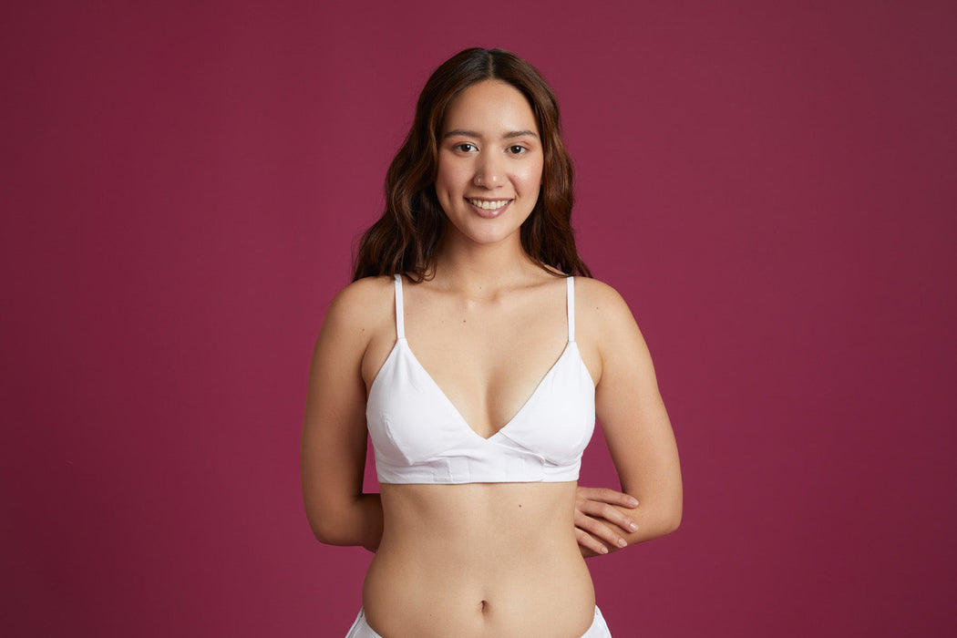 Front angle of a model wearing Slick Chicks Adaptive Wireless Front Fastening Bra in white against a plum background