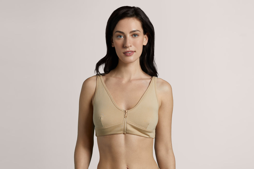 Front angle of a model wearing Slick Chicks Adaptive Wireless Front Zip Bra in beige against a beige background