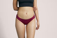 Front angle of a model wearing Slick Chicks Adaptive Bikini Brief Panty in plum against a plain light beige studio background