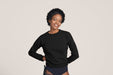 Front angle of a smiling woman with short black curly hair wearing Slick Chicks Adaptive Crewneck Sweatshirt in black, against a solid beige background