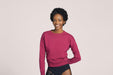 Front angle of a smiling woman with short black curly hair wearing Slick Chicks Adaptive Crewneck Sweatshirt in plum, against a solid beige background