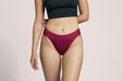 Front angle of a model wearing Slick Chicks Adaptive High Waist Brief in plum against a plain light beige studio background