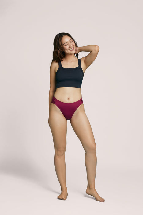 A model wearing Slick Chicks Adaptive High Waist Brief in plum against a plain light beige studio background