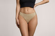 Front angle of a model wearing Slick Chicks Adaptive High Waist Brief in beige against a plain light beige studio background