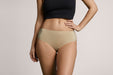 Front angle of a model wearing Slick Chicks Adaptive Hipster Panty in beige against a plain light beige studio background