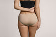 Back angle of a model wearing Slick Chicks Adaptive Hipster Panty in beige against a plain light beige studio background