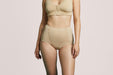 Front angle of a model wearing Slick Chicks Adaptive Leakproof Underwear in beige against a plain light beige studio background