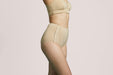 Side angle of a model wearing Slick Chicks Adaptive Leakproof Underwear in beige against a plain light beige studio background