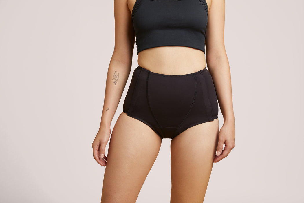 Front angle of a model wearing Slick Chicks Adaptive Leakproof Underwear in black against a plain light beige studio background