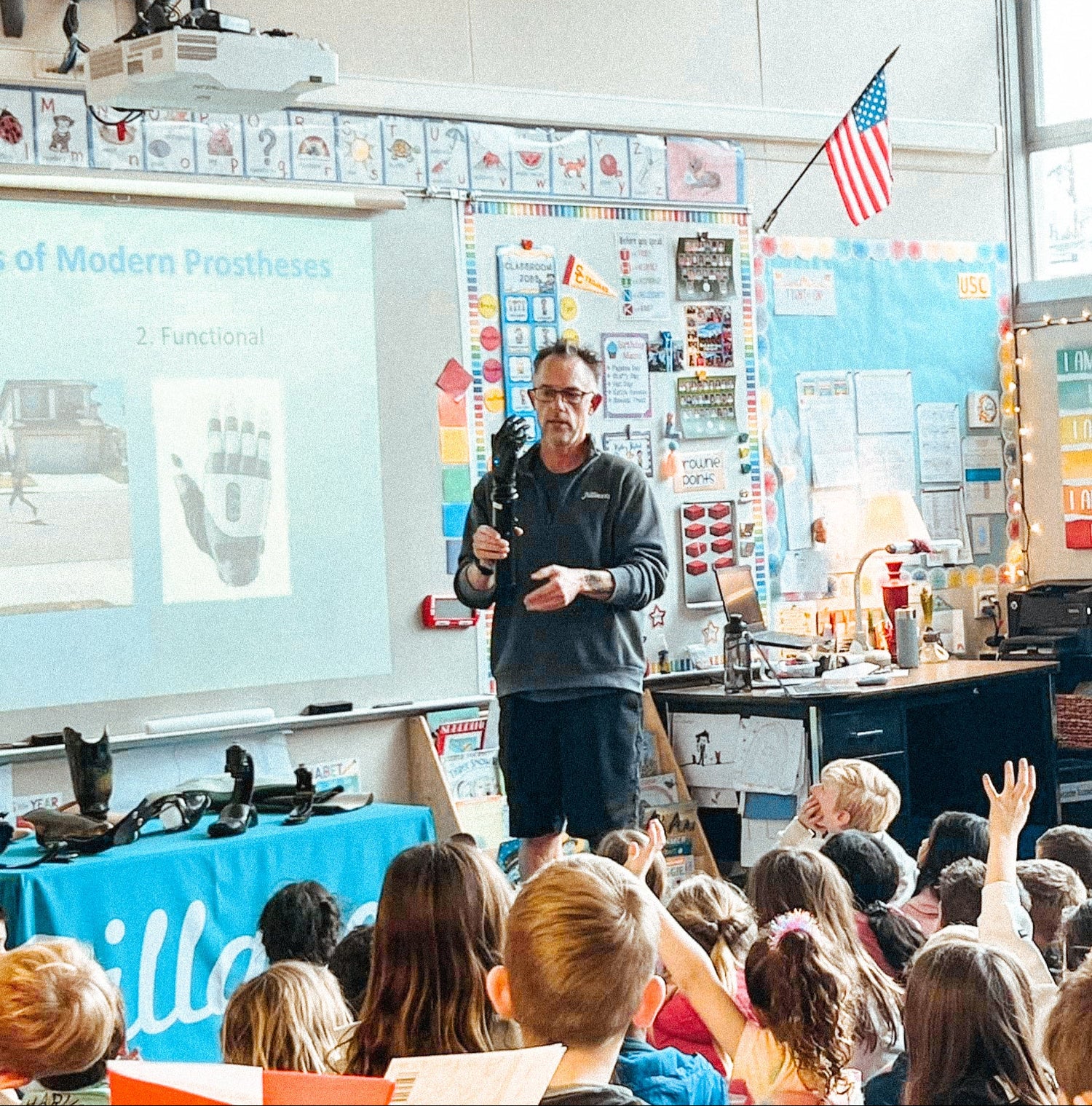 Andrew May giving a presentation to a class of students in a classroom about prosthetics.