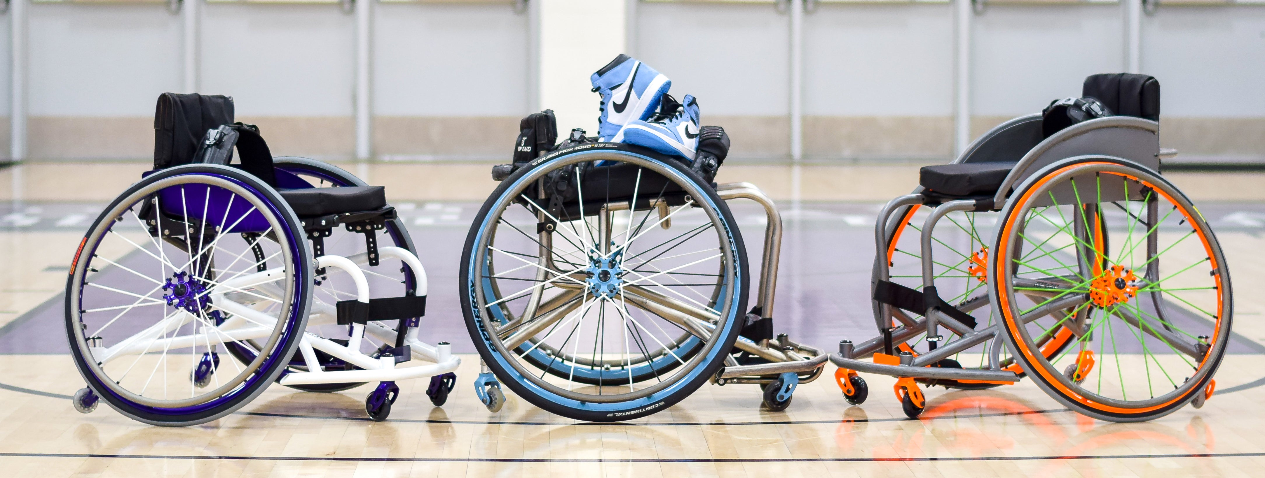 Three Top End Basketball Wheelchairs lined up together on a basketball court