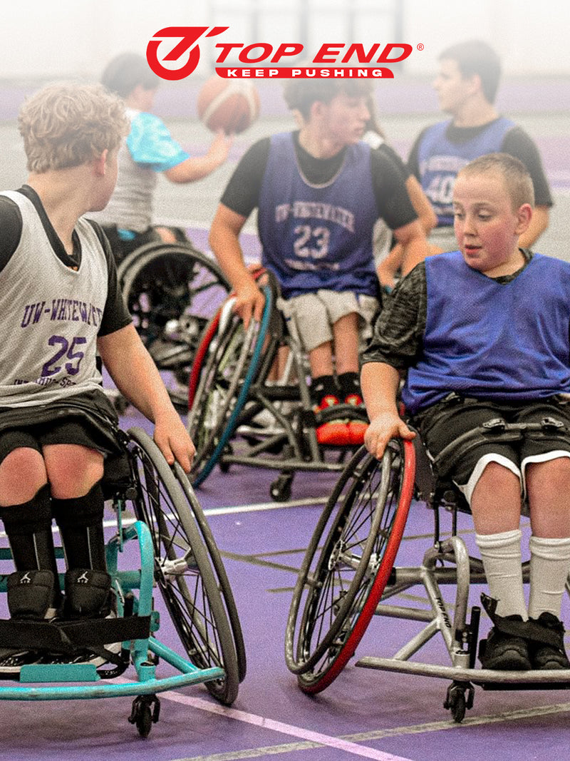 Children in Top End basketball wheelchairs playing on a basketball court.
