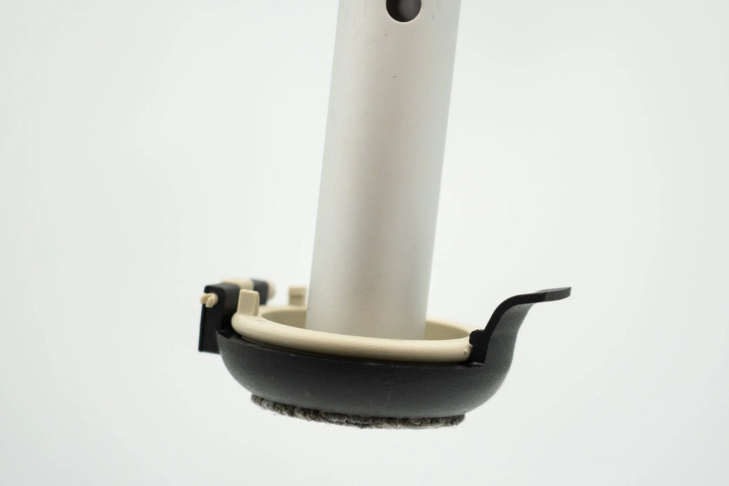 Versa Select walker footing on a walker leg with the hinged black coaster folded down under the tan base puck and its quick release tab at the side, on a white background