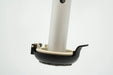 Versa Select walker footing on a walker leg with the hinged black coaster folded down under the tan base puck and its quick release tab at the side, on a white background