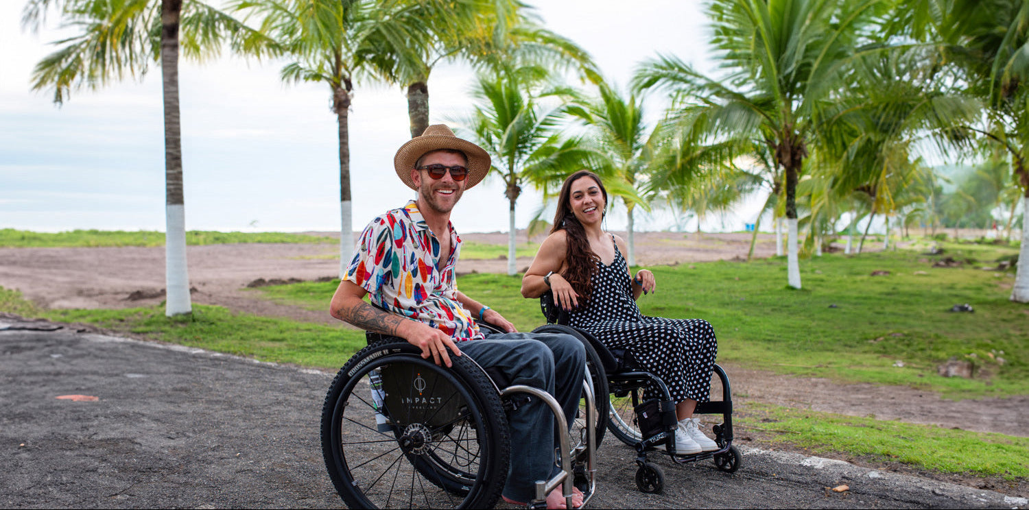 Two people using wheelchairs in a park with palm trees in the background