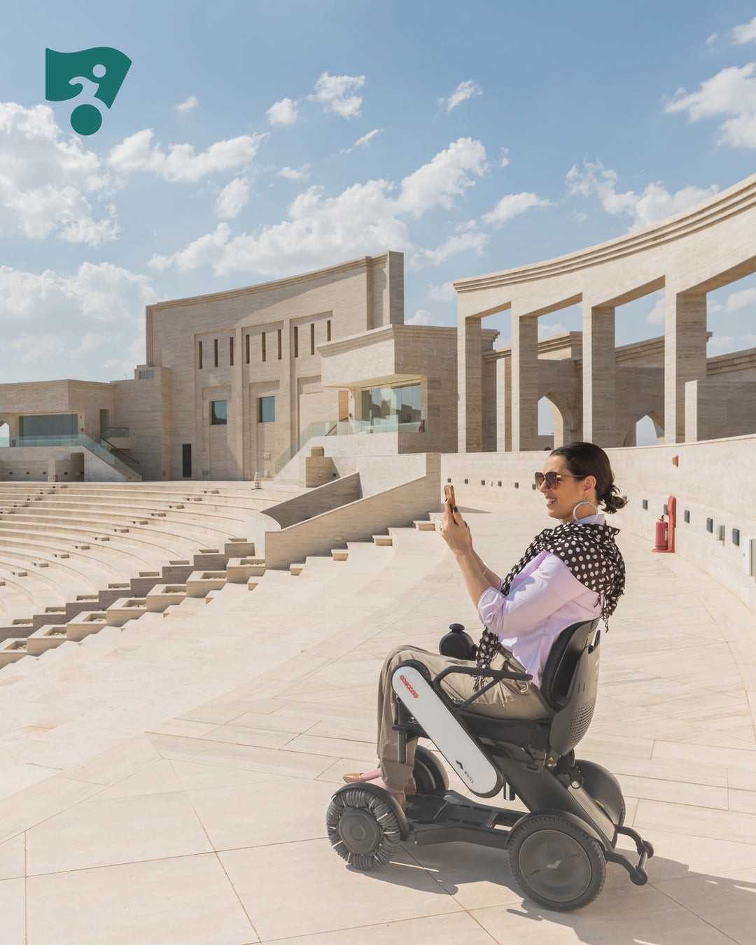 Person using a mobility device in an outdoor setting with architectural background.