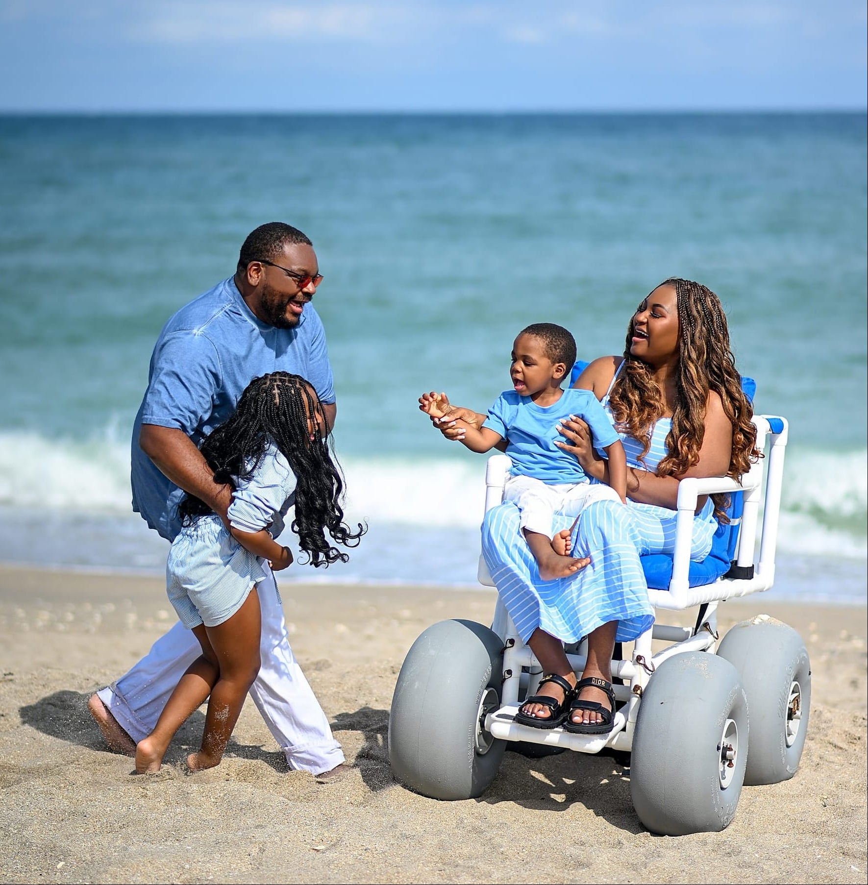 Family with a child in a beach wheelchair at the ocean
