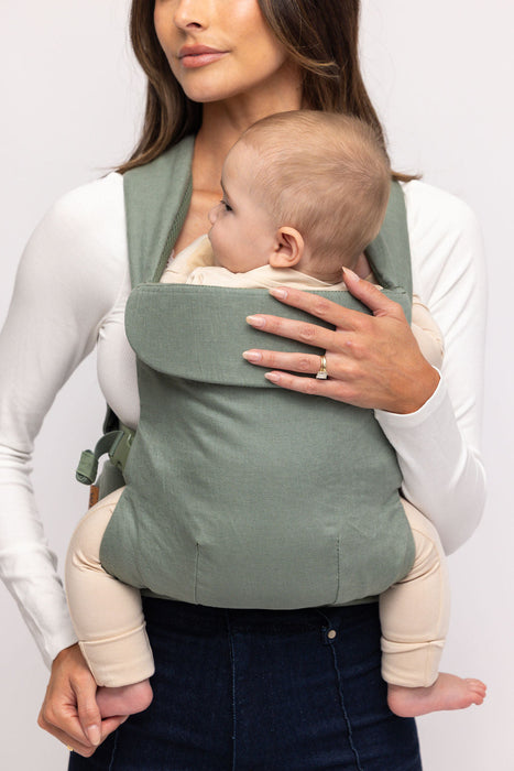 Detail of woman holding a baby in a WildBird Acadian Aerial Buckle Baby Carrier on a white background