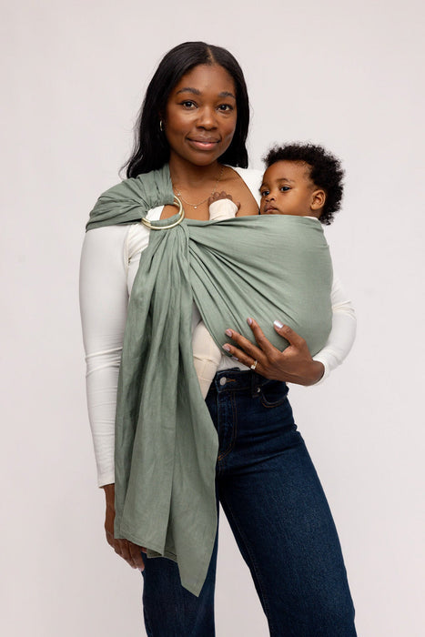 Woman holding a baby in a WildBird Acadian Linen Baby Sling on a white background