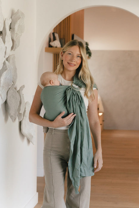 Woman holding a baby in a WildBird Acadian Linen Baby Sling in a home setting