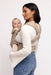 Back of woman holding a baby in a WildBird Desert Lark Aerial Buckle Baby Carrier on a white background