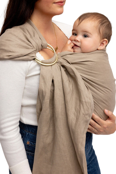 Front side detail of woman holding a baby in a WildBird Desert Lark Linen Baby Sling on a white background