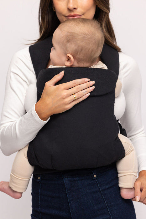Detail of woman holding a baby in a WildBird Raven Aerial Buckle Baby Carrier on a white background