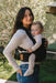 Woman holding a baby in a WildBird Raven Aerial Buckle Baby Carrier outdoors