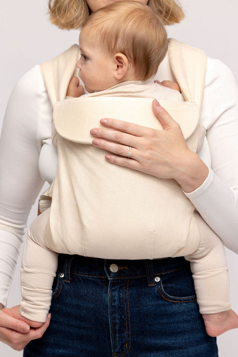 Detail of woman holding a baby in a WildBird Sparrow Aerial Buckle Baby Carrier on a white background