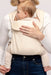 Detail of woman holding a baby in a WildBird Sparrow Aerial Buckle Baby Carrier on a white background