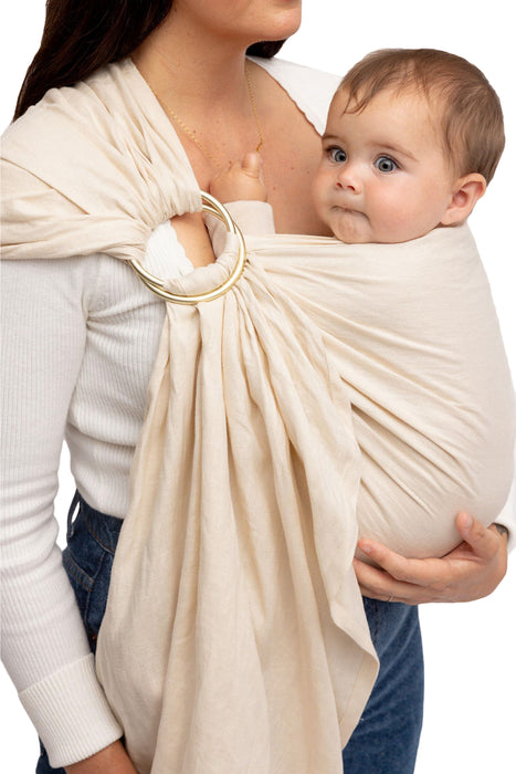 Front side detail of woman holding a baby in a WildBird Sparrow Linen Baby Sling on a white background
