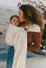 Woman holding a baby in a WildBird Sparrow Linen Baby Sling outdoors with flowers in the background