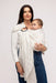 Woman holding a baby in a WildBird Swan Linen Baby Sling on a white background
