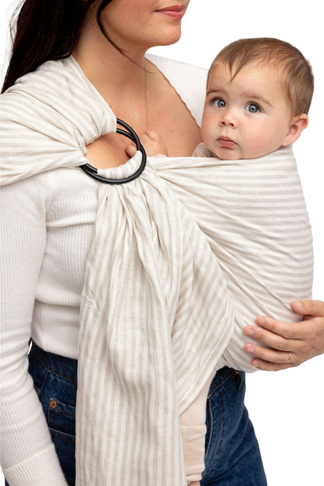 Front side detail of woman holding a baby in a WildBird Swan Linen Baby Sling on a white background