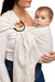 Front side detail of woman holding a baby in a WildBird Swan Linen Baby Sling on a white background