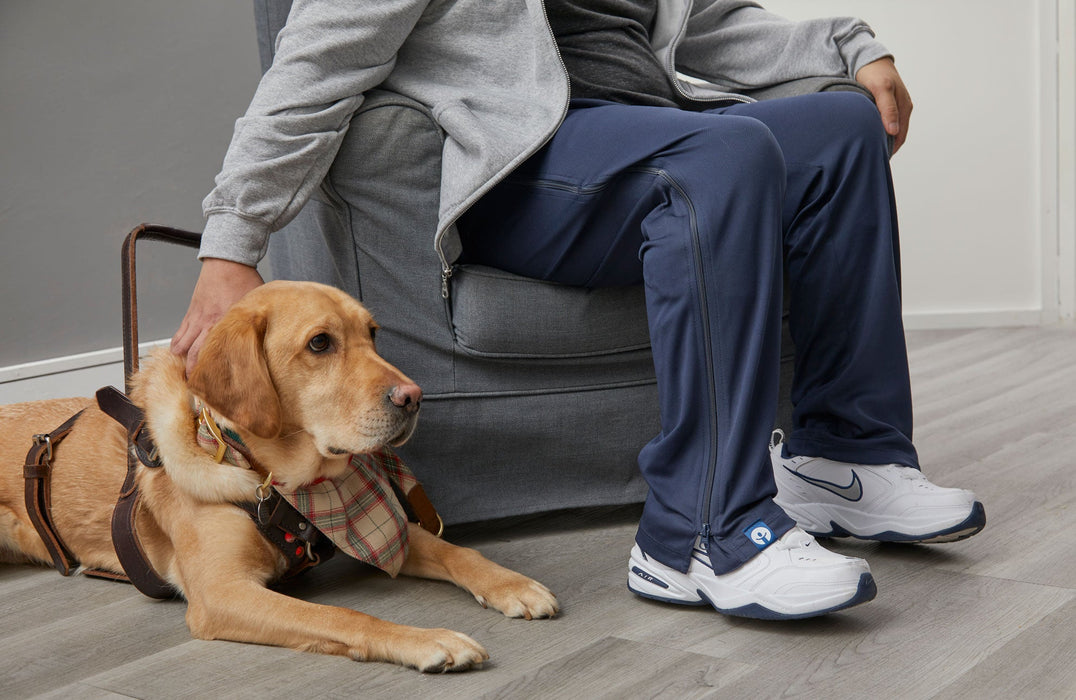 Person sitting on a couch with a dog wearing the befree zipOns Adult Lightweight Adaptive Pants
