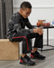 Child sitting on a box wearing the befree zipOns Youth Heavyweight Adaptive Pants with a table and snacks in the background