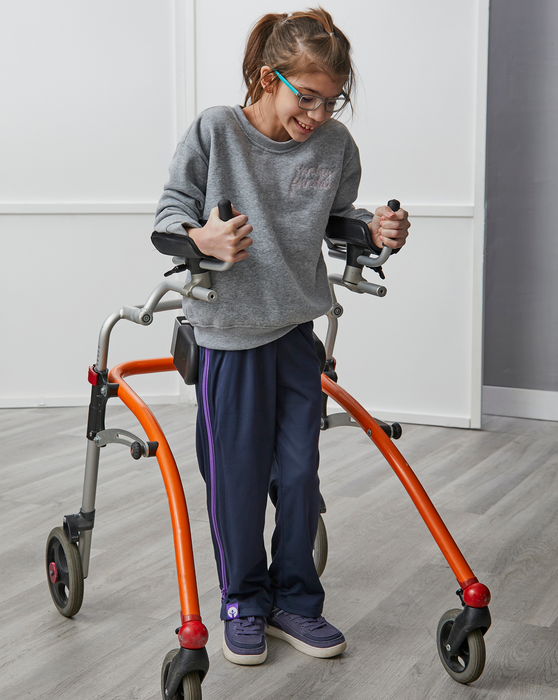 Person using a walker with orange legs in a room while wearing the befree zipOns Youth Heavyweight Adaptive  Pants and Billy Footwear