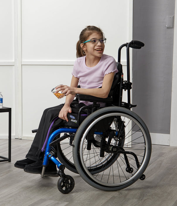 Young girl in a wheelchair smiling indoors while wearing the befree zipOns Youth Heavyweight Adaptive Pants