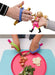 Children's toy utensils with dolls and a plate of food with an EaZyHold Grip Aid on a white background