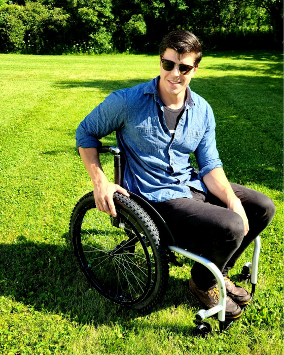 Person in a wheelchair on grass with trees in the background