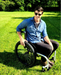 Person in a wheelchair on grass with trees in the background