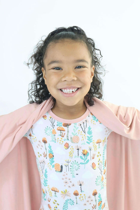 Child smiling while holding a Rainn Bamboo Fern Blanket on a white background