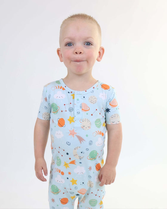 Child smiling while wearing a Rainn Bamboo Cosmic Pull Up Romper on a white background
