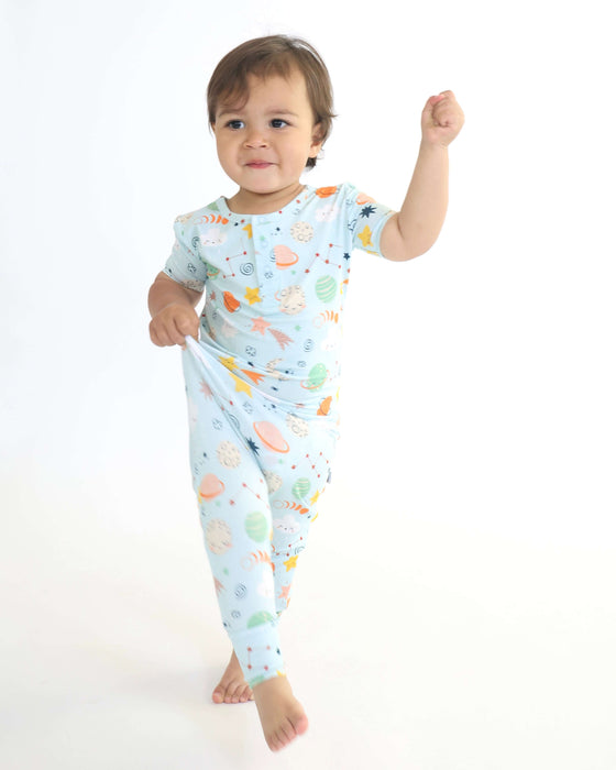 Child standing while wearing a Rainn Bamboo Cosmic Pull Up Romper on a white background