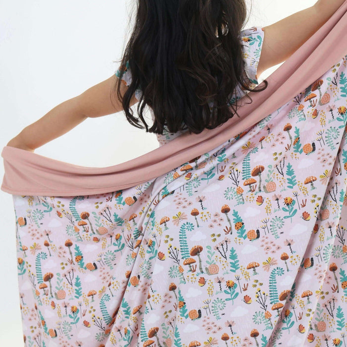 Child spreading out a Rainn Bamboo Fern Blanket on a white background